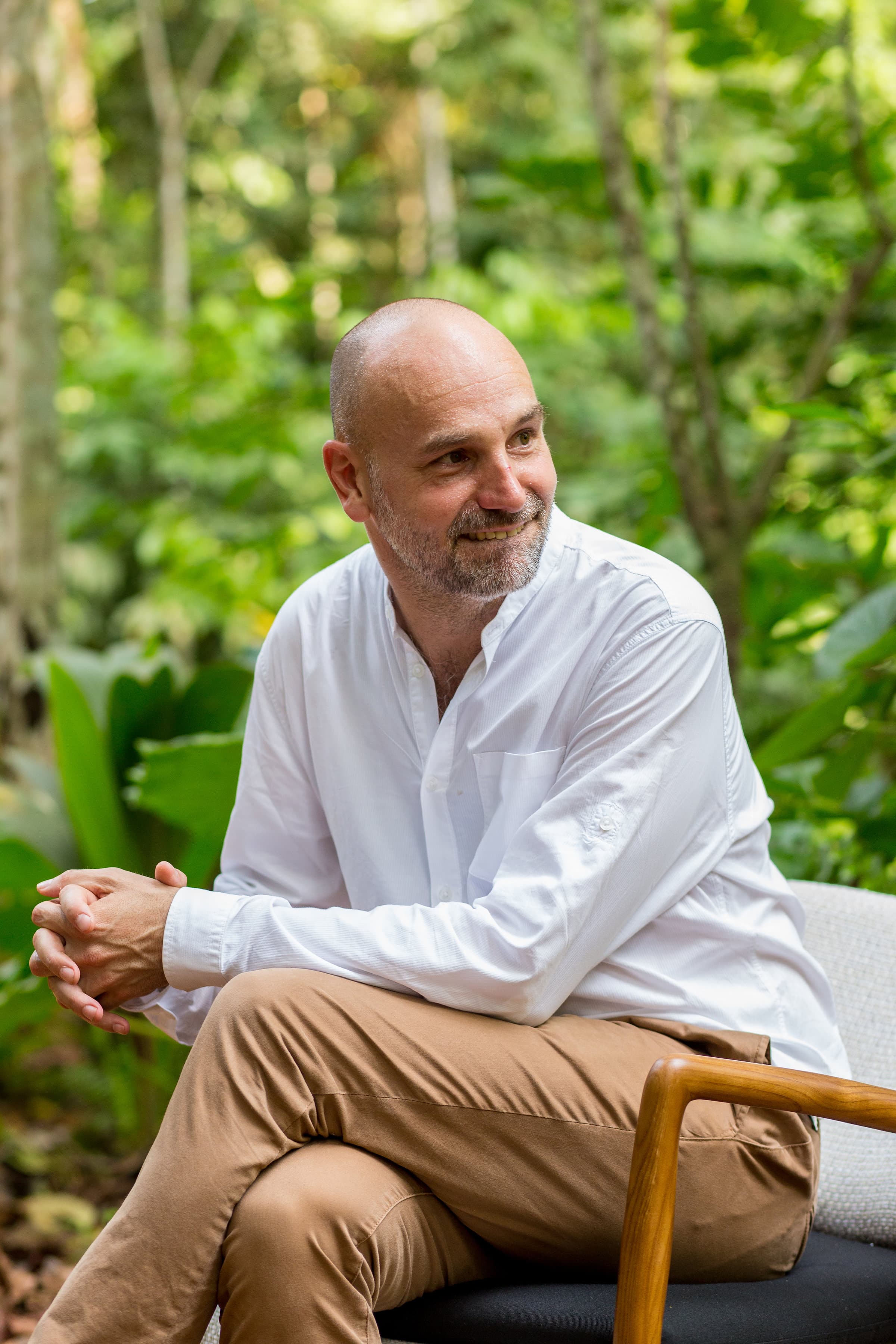 Mark Shuttleworth com camisa branca sentado diante de densa vegetação verde na Ilha do Príncipe